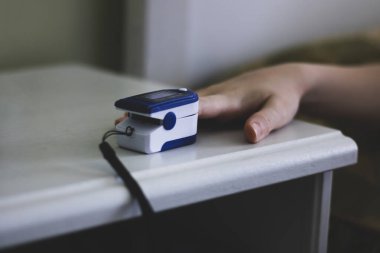 Oksijen doygunluğunu ölçen taşınabilir nabız oksimetresi. Yatak odasındaki parmaklarda nabız oksimetresi..