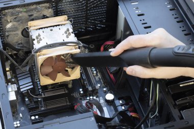 Bilgisayarın içinde çok kirli bir bilgisayar vantilatörü elektrikli süpürgeyle temizleniyor..