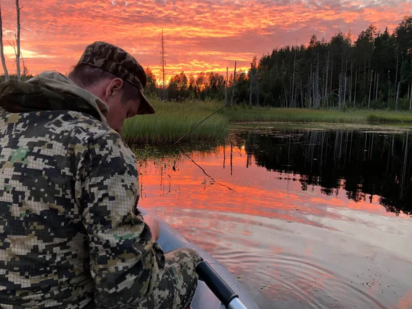 Un pescador se sienta en un barco al atardecer en el lago, tranquilo —  Fotos de Stock