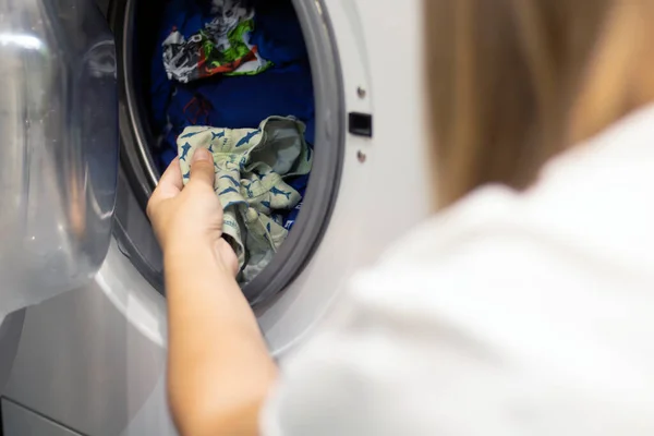 El çamaşır makinesinden çıkar ve bebeğin çamaşırlarını yıkar. Seçici odak, yakın plan