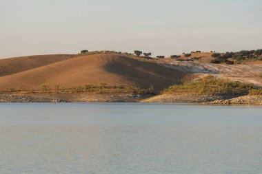 Portekiz, Terena 'da gün batımında baraj gölü rezervuarındaki suyun yansımasıyla çöl gibi.