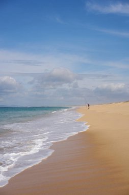 Portekiz 'de kumsalda okyanus dalgaları olan Comporta' da balık tutan bir balıkçı.
