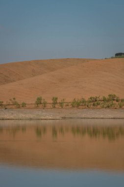 Portekiz, Terena 'da mavi gökyüzü olan baraj gölü rezervuarındaki suya yansıyan tepe manzarası gibi çöl.
