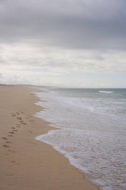 Portekiz, Comporta 'da kumların üzerinde ayak sesleri ve okyanus dalgaları olan vahşi, boş bir sahil.