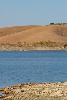 Portekiz, Terena 'da mavi gökyüzü olan baraj gölü rezervuarındaki suya yansıyan tepe manzarası gibi çöl.