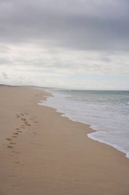 Portekiz, Comporta 'da kumların üzerinde ayak sesleri ve okyanus dalgaları olan vahşi, boş bir sahil.