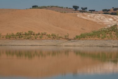 Portekiz, Terena 'da mavi gökyüzü olan baraj gölü rezervuarındaki suya yansıyan tepe manzarası gibi çöl.