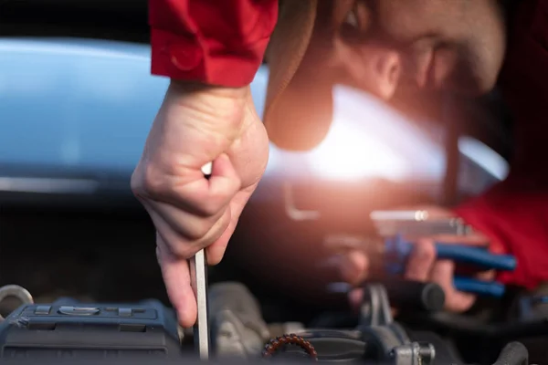 Emergency roadside assistance, road assistance worker in uniform trying to fix car breakdown or engine failure.  Roadside assistance concept