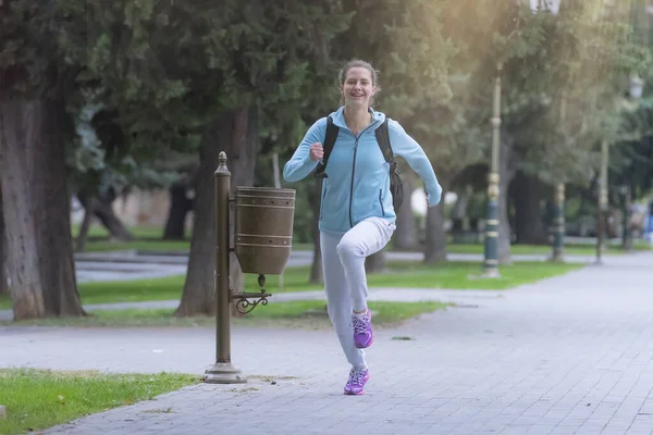 Healthy lifestyle woman running at city park pavement. Girl wearing sportswear doing fitness activities outdoors. Healthy lifestyle and sport concepts