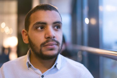 African Man Looking at Window in Cafe. Looking through the window, gaining inspiration in urban landscape outside