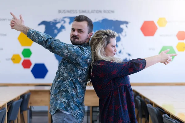 Two college students standing inside classroom and posing for photoshooting after lecture.