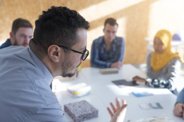Erkek mimari profesörü çok ırklı öğrencilere ders veriyor ve onlarla modern sınıfta etkileşim kuruyor. Ders sırasında öğrencilere yardım ediyor..