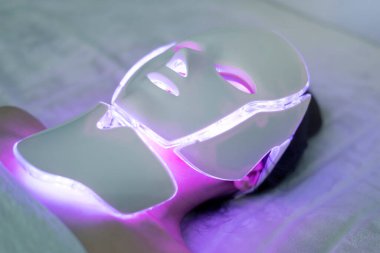Kozmetik maske. Kız maske takıyor. Promosyon ürünleri. Yüzün sağlığı ve güzelliği. LED Yüz Maskesi, Güzellik Fotonu Terapisi. LED maskeli yenileme tedavisi genç bir kadına uygulanır.
