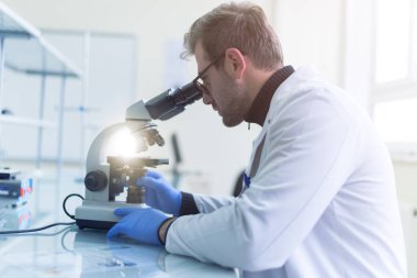 Laboratuvarda test tüpü ya da mikroskop tutan bir bilim adamı, koronavirüs enfeksiyonu için tedavi ya da aşı buluyor. Covid-19, laboratuvar ve aşı konsepti.