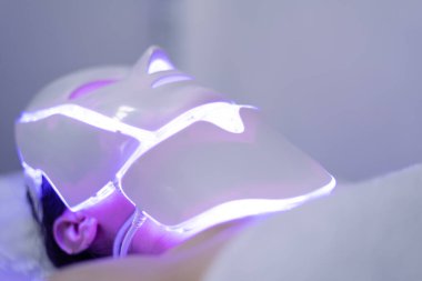 Foton maskesi. Sağlık ve güzellik. Kadın yüzü için estetik ameliyat. Güzellik laboratuarı. LED Yüz Maskesi, Foton Terapisi. Fotoğraf farklı kipleri, renkleri gösterir