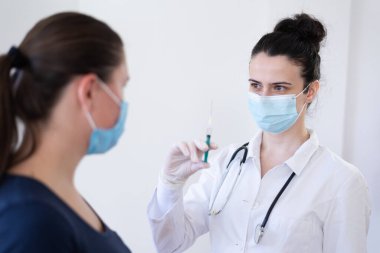 Klinikteki pratisyen hekimin aşısı. Doktor, hastanede yaşlı kadına iğne yapıyor. Covid-19 ya da Coronavirus aşısı yapmadan önce elinde şırınga tutan hemşire..