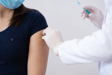 Klinikteki pratisyen hekimin aşısı. Doktor, hastanede yaşlı kadına iğne yapıyor. Covid-19 ya da Coronavirus aşısı yapmadan önce elinde şırınga tutan hemşire..