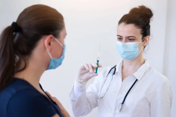 General practitioner vaccinating  patient in clinic. Doctor giving injection to senior woman at hospital. Nurse holding syringe before make Covid-19 or coronavirus vaccine.