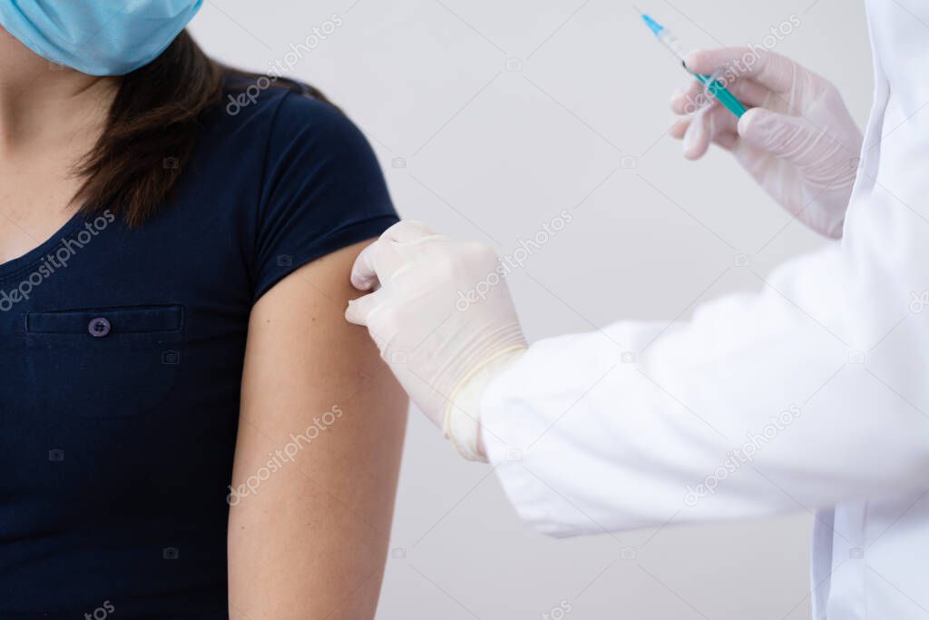 General practitioner vaccinating  patient in clinic. Doctor giving injection to senior woman at hospital. Nurse holding syringe before make Covid-19 or coronavirus vaccine.