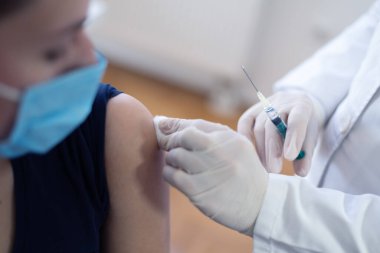 Klinikteki pratisyen hekimin aşısı. Doktor, hastanede yaşlı kadına iğne yapıyor. Covid-19 ya da Coronavirus aşısı yapmadan önce elinde şırınga tutan hemşire..