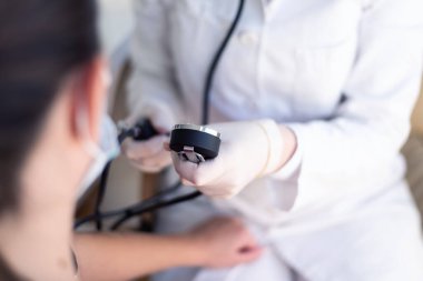 Steteskopla sphygmomanometre kullanan kadın doktor. Hastanedeki bir hastanın tansiyonunu ölçüyor.