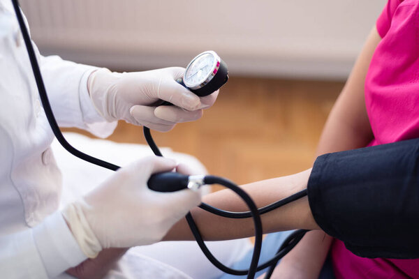 Female doctor using sphygmomanometer with stethoscope checking blood pressure to a patient in the hospital