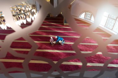 Müslüman baba ve oğul birlikte dua ediyorlar. Müslüman baba ve oğul camide namaz kılıyor ve camide Kuran okuyorlar..
