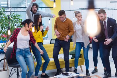 İş kazananlar. Bir grup mutlu genç kutlama yapıyor, el kol hareketi yapıyor, kollarını kaldırıyor ve pozitifliğini ifade ediyor.