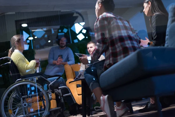 Office workers and person in a wheelchair discussing business moments in a modern office. Disability and business concept