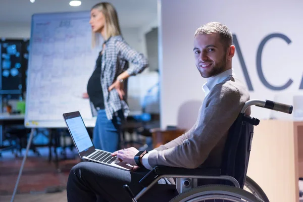 Office workers and person in a wheelchair discussing business moments in a modern office. Disability and business concept