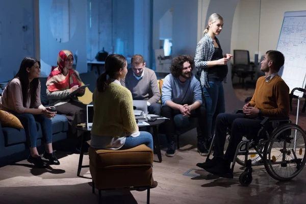 Office workers and person in a wheelchair discussing business moments in a modern office. Disability and business concept