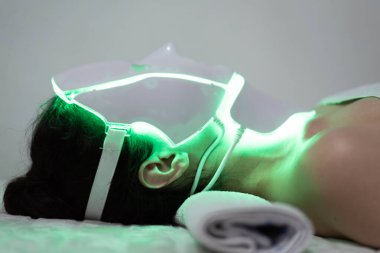 Yüz terapisi ve boyun maskesi foton terapisi gören bir kadın. Ev cildi ve benim zaman kavramım