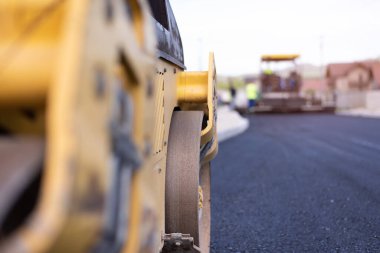 Modern ağır asfalt rulo yığınları ve sıcak asfalta basmak. Sarı yol tamir makinesi. Modern şehirde titreşim silindirli sıkıştırıcı ile tamir ediliyor.