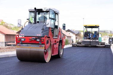 Modern ağır asfalt rulo yığınları ve sıcak asfalta basmak. Sarı yol tamir makinesi. Modern şehirde titreşim silindirli sıkıştırıcı ile tamir ediliyor.
