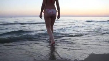 Güzel vücutlu genç bir kadın denize giriyor.