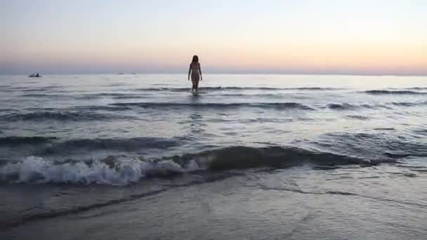 Молодая женщина с красивой фигурой входит в море — стоковое видео