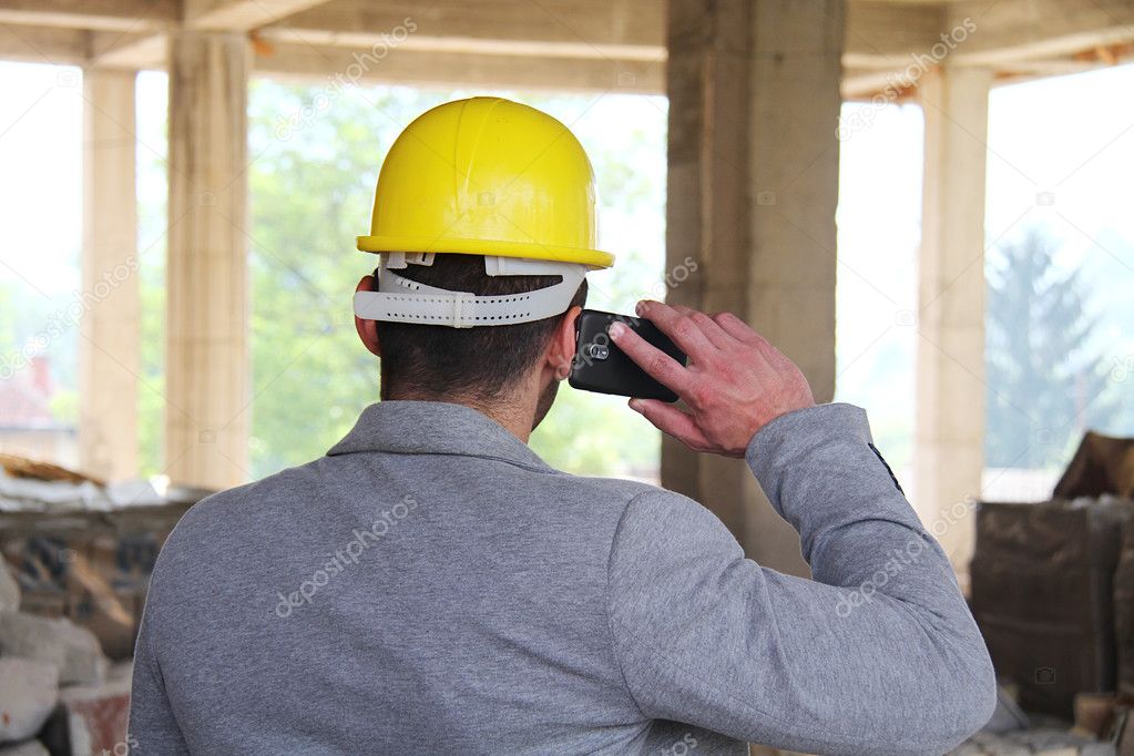 Engineer at a construction site making a business call