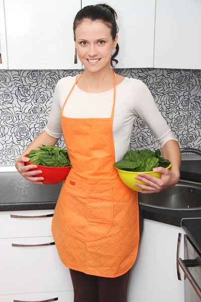 Žena s špenát v moderní kuchyni. — Stock fotografie