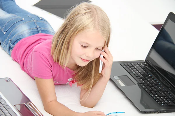 Little child playing at home with tablet, laptop and phone Stock Image