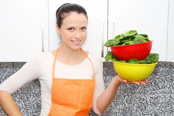 Žena s špenát v moderní kuchyni. — Stock fotografie