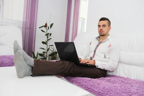 El hombre joven exitoso con el ordenador portátil en casa — Foto de Stock