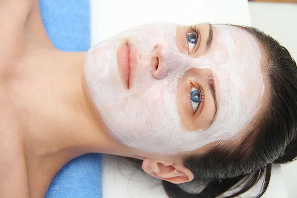 Mooie jonge blauwe ogen vrouw met klei gezichtsmasker — Stockfoto