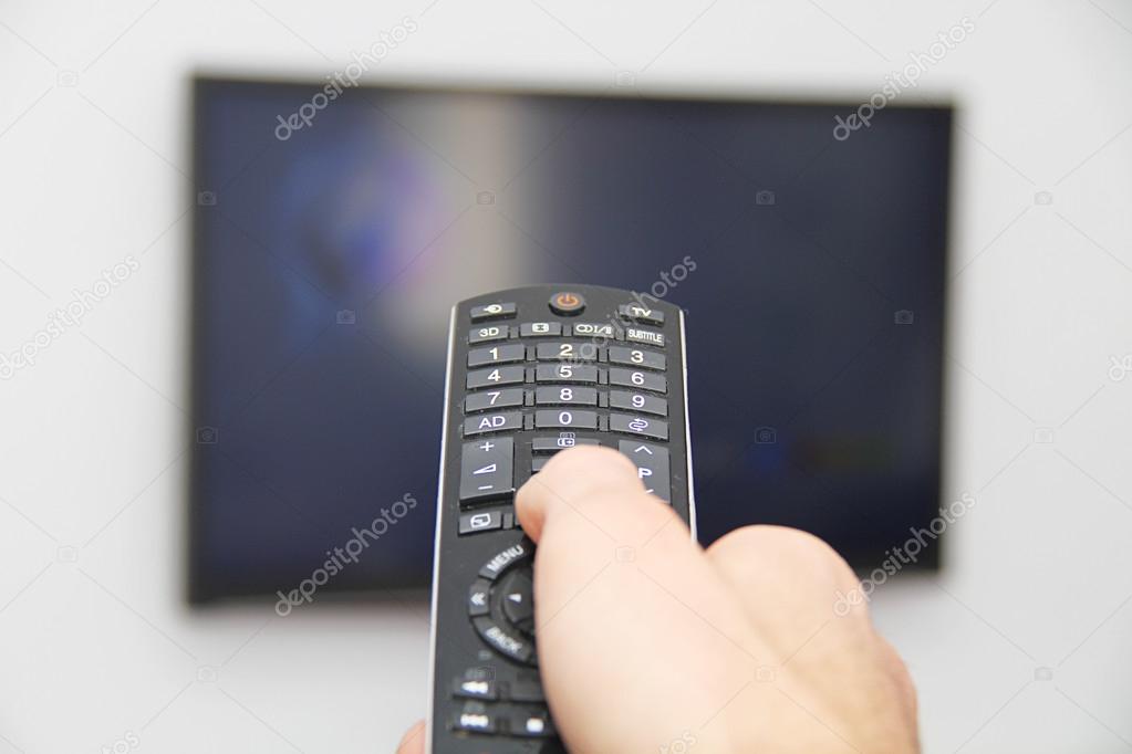 Young man sitting on the couch watching a football game on tv