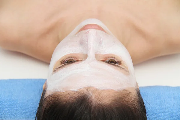 Mooie jonge blauwe ogen vrouw met klei gezichtsmasker — Stockfoto