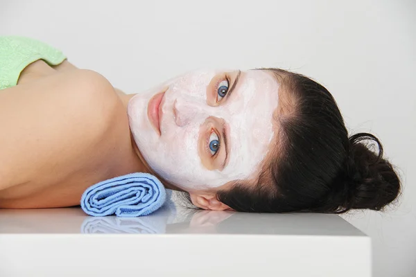 Mooie jonge blauwe ogen vrouw met klei gezichtsmasker — Stockfoto