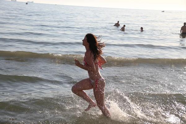 Mujer atractiva joven corriendo a lo largo de la orilla del mar — Foto de Stock