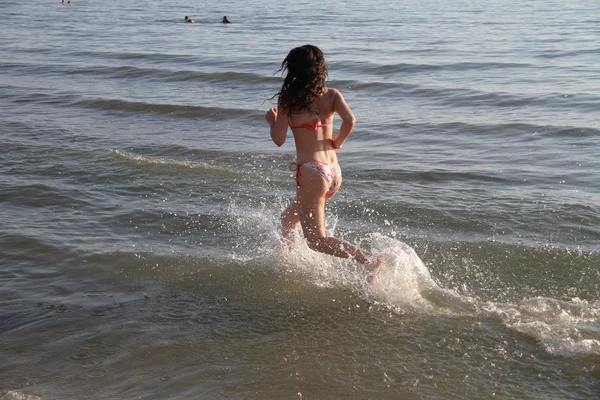 Mujer atractiva joven corriendo a lo largo de la orilla del mar — Foto de Stock