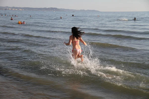 Mujer atractiva joven corriendo a lo largo de la orilla del mar — Foto de Stock