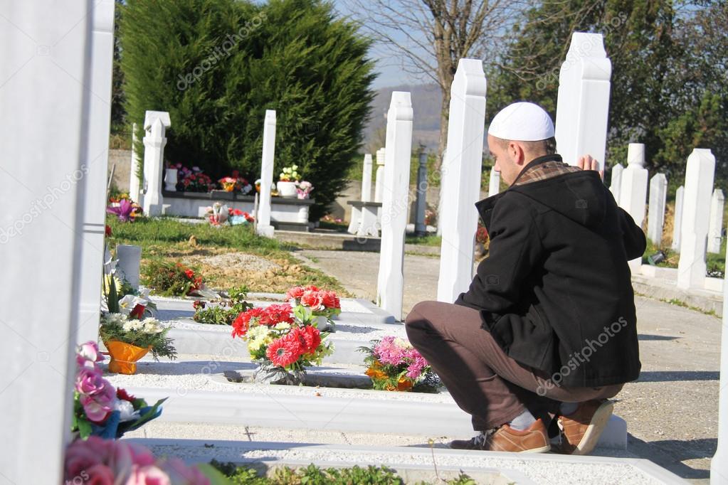 Young muslim man near the his father grave