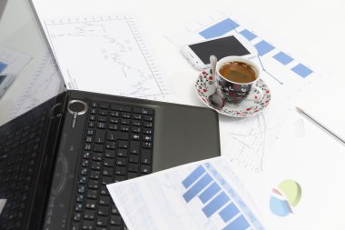 Kahve ve dizüstü bilgisayarlı bir işadamı izleme cihazını inceliyor.